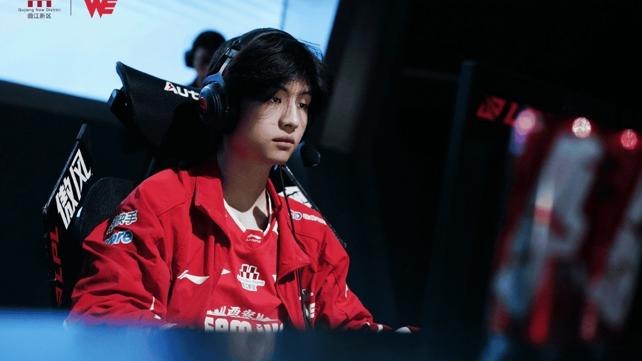Team WE jungler Monki sits at his computer in a red team jacket
