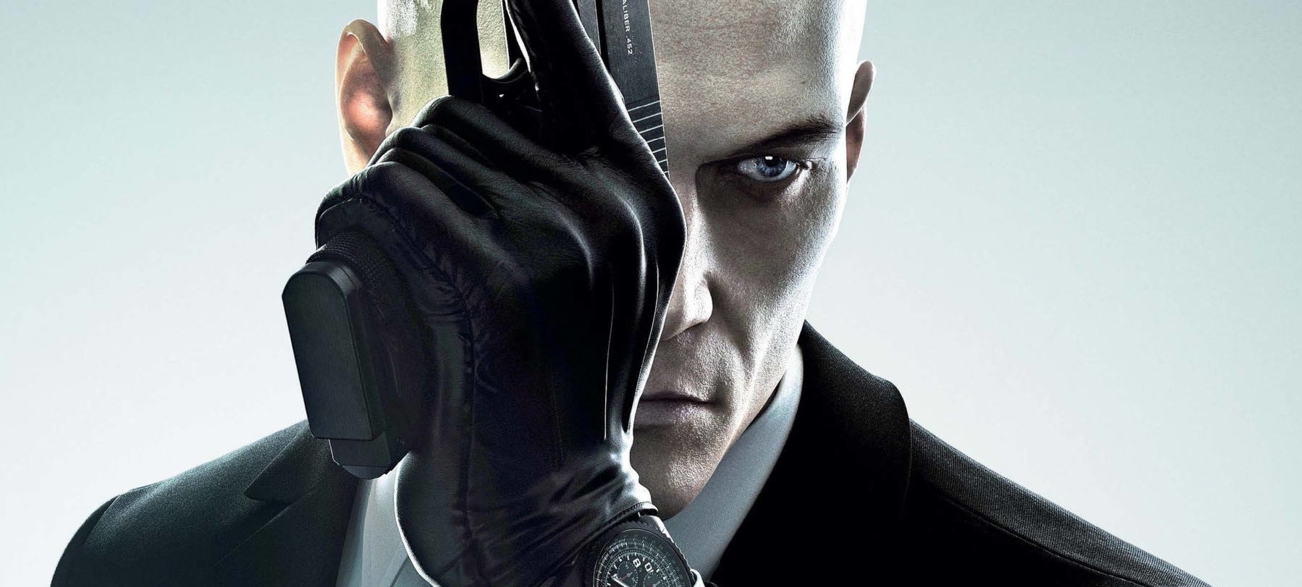 Close-up of Agent 47 holding a pistol in a modern promotional image from the Hitman franchise